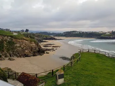 a beach with a fence next to the ocean at Playa Ribeiría apartamento vacacional in Tapia de Casariego