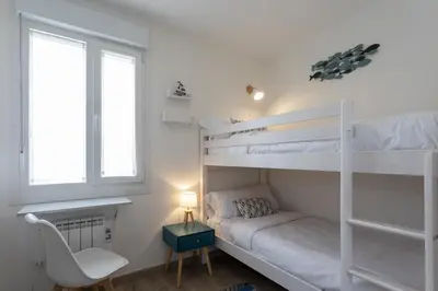 a bedroom with bunk beds with a chair and a desk at Playa Ribeiría apartamento vacacional in Tapia de Casariego