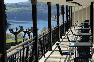a row of chairs on a balcony overlooking a lake at Hotel Villa Jardín in Portomarin