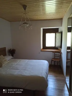 a bedroom with a bed and a window and a chandelier at CASA DA LOAIRA in Quiroga