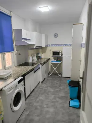 a large kitchen with white cabinets and a washer at Tonos de Azul in Ponferrada