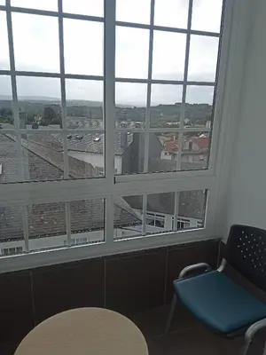 a room with a large window with a chair and a table at Pensión KM66 Palas de Rei in Palas de Rei