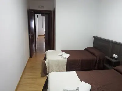 a hotel room with two beds and a hallway at Pensión KM66 Palas de Rei in Palas de Rei
