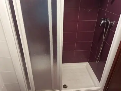 a shower in a bathroom with purple tiles at Pensión KM66 Palas de Rei in Palas de Rei