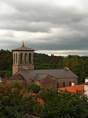 an old church with a clock tower in the distance at Pensión KM66 Palas de Rei in Palas de Rei