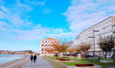 two people walking down a sidewalk in front of buildings at Viveiro Histórico 2 in Viveiro