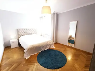 a bedroom with a bed and a blue rug and a mirror at Viveiro Histórico 2 in Viveiro