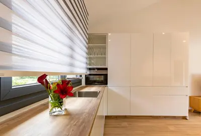 a kitchen with white cabinets and a vase with red flowers at Aires De Míguez in Jove