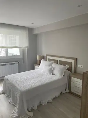 a white bedroom with a bed with white sheets and pillows at Golden Views in Viveiro