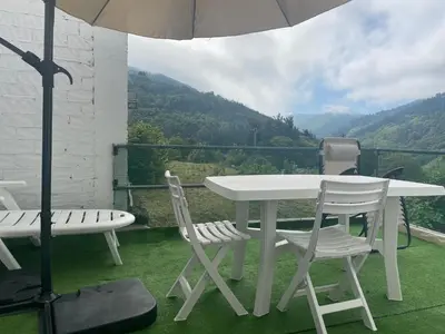 a table and two chairs and an umbrella on a balcony at Minâ in Taramundi