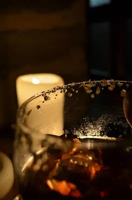 a drink being poured into a glass next to a candle at La Hoja de Roble in Puebla de Sanabria