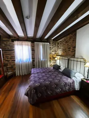a bedroom with a large bed and a brick wall at La Hoja de Roble in Puebla de Sanabria