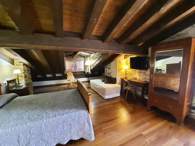 a bedroom with a bed and a couch and a television at La Hoja de Roble in Puebla de Sanabria