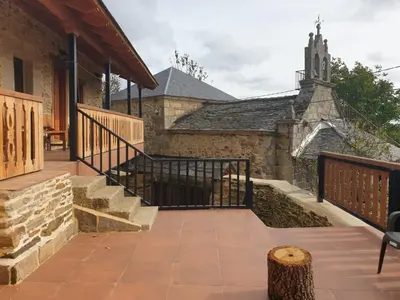 an outdoor patio with stairs and a church at Casa la ti María la viuda in Riego de Lomba