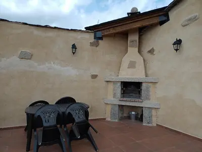 a patio with chairs and an outdoor pizza oven at Casa la ti María la viuda in Riego de Lomba