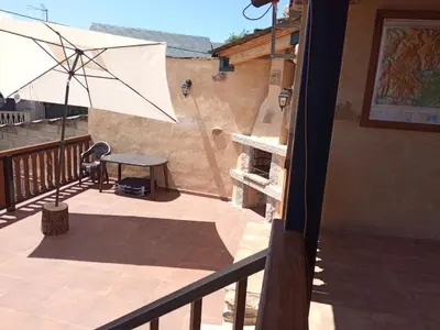 a patio with a table and an umbrella on a balcony at Casa la ti María la viuda in Riego de Lomba