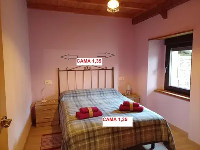 a bedroom with a bed with two price signs on it at Casa la ti María la viuda in Riego de Lomba