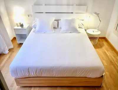 a large bed with white sheets and pillows in a room at The Cliffs - Sunset Village Beach 1A in Viveiro