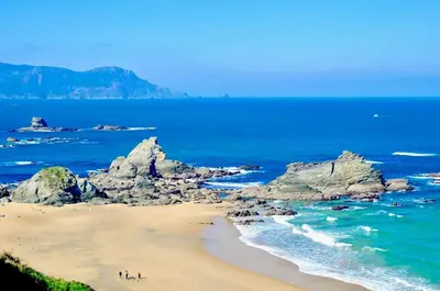 people on a beach with rocks in the ocean at The Cliffs - Sunset Village Beach 1A in Viveiro