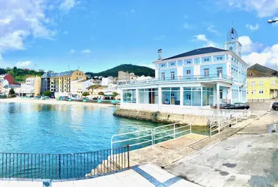 a large white building next to a body of water at The Cliffs - Sunset Village Beach 1C in Viveiro