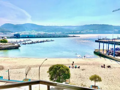 a beach with people in the water and a pier at The Cliffs - Sunset Village Beach 1D in Viveiro