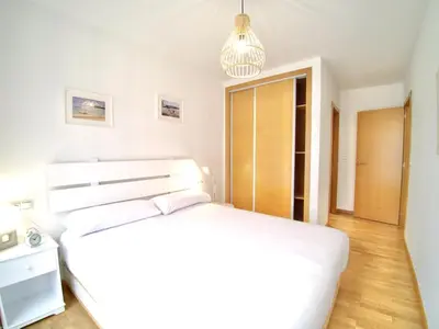 a white bedroom with a bed and a pendant light at The Cliffs - Sunset Village Beach 1D in Viveiro