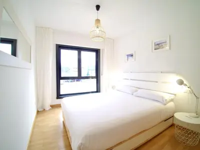a white bedroom with a large bed and a window at The Cliffs - Sunset Village Beach 1D in Viveiro