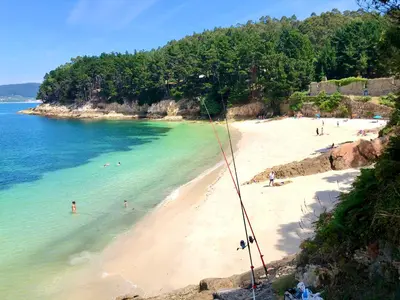 a beach with a group of people in the water at The Cliffs - Sunset Village Beach 1D in Viveiro
