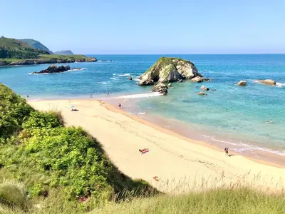a beach with people swimming in the ocean at The Cliffs - Sunset Village Beach 1D in Viveiro