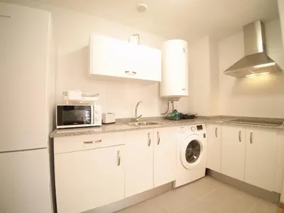 a kitchen with white cabinets and a washer and dryer at The Cliffs - Sunset Village Beach 3C in Viveiro