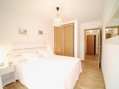 a white bedroom with a white bed and a hallway at The Cliffs - Sunset Village Beach 3C in Viveiro