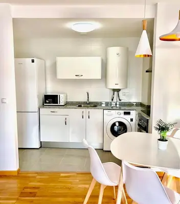 a kitchen with white appliances and a table and chairs at The Cliffs - Sunset Village Beach 3C in Viveiro