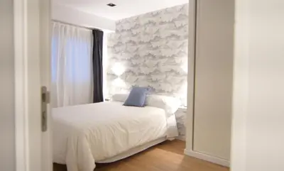 a bedroom with a white bed with a blue pillow at NOBE ROOMS in Santiago de Compostela