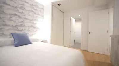 a bedroom with a bed with a blue pillow on it at NOBE ROOMS in Santiago de Compostela