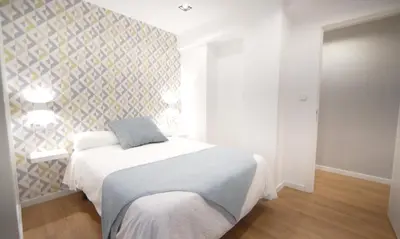a bedroom with a bed and a wall at NOBE ROOMS in Santiago de Compostela