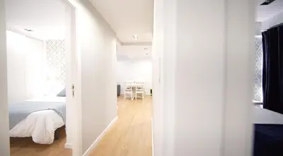 a white bedroom with a bed and a table at NOBE ROOMS in Santiago de Compostela