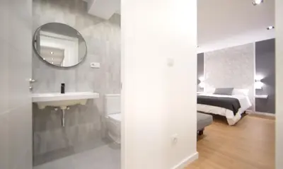 a bathroom with a sink and a mirror and a bed at NOBE ROOMS in Santiago de Compostela