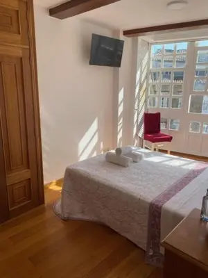 a bedroom with a bed and a red chair at entrepraciñas 1 in Santiago de Compostela