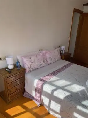a bedroom with a bed and a wooden dresser with a lamp at entrepraciñas 1 in Santiago de Compostela