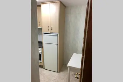 a small kitchen with a white refrigerator and a table at entrepraciñas 2 in Santiago de Compostela