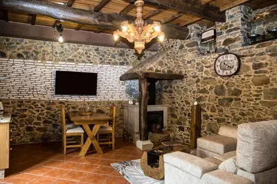 a living room with a stone wall with a tv at CASA PITAXAN in Melide