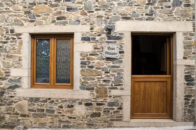 a stone building with two windows and a wooden door at CASA PITAXAN in Melide