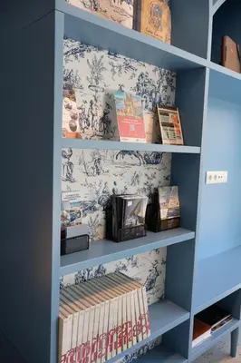 a book shelf filled with books with blue and white wallpaper at Loop INN Hostel Santiago de Compostela in Santiago de Compostela