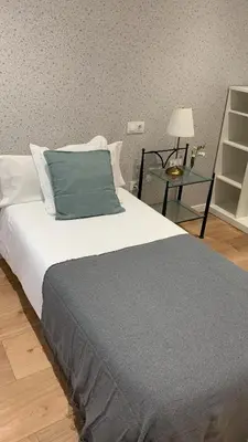 a bedroom with a bed with a blue pillow and a table at Campo de Estrellas in Santiago de Compostela