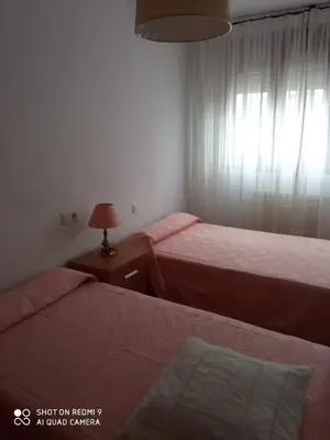a bedroom with two beds and a table with a lamp at APARTAMENTO RAFER in Ribadeo