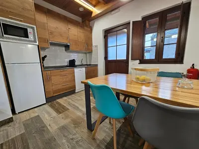 a kitchen with a wooden table and a refrigerator at Apartamentos Rurales Lola Penarronda in Castropol