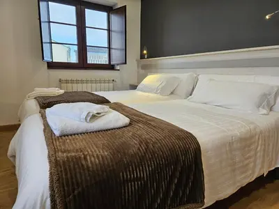 a bedroom with two beds with white sheets and a window at Apartamentos Rurales Lola Penarronda in Castropol
