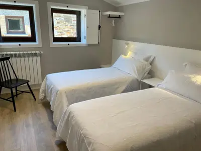 a bedroom with two beds and a chair and a window at Casa Galego in Fonfría