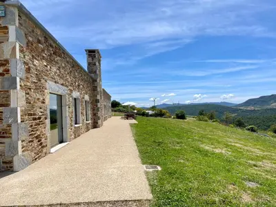 a brick building with a bench on a grassy hill at Casa Galego in Fonfría