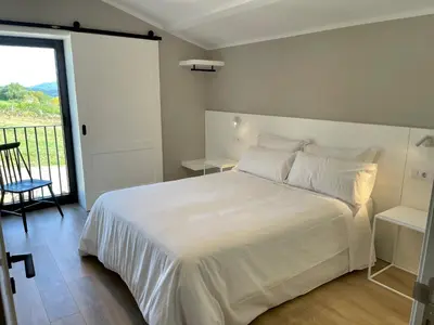 a bedroom with a white bed and a balcony at Casa Galego in Fonfría